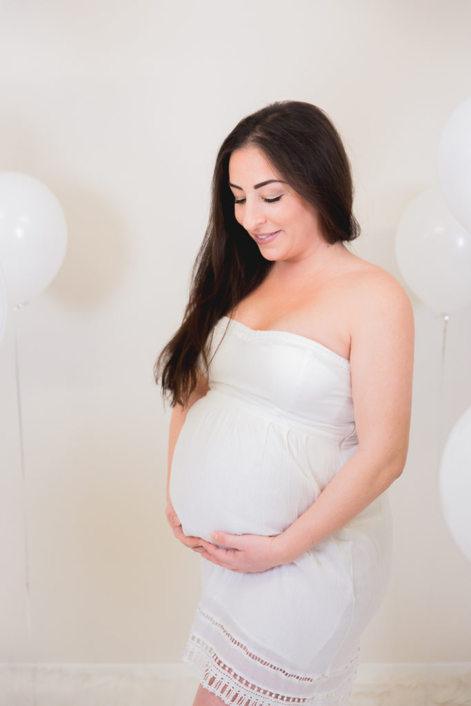 Lachend werdende Mutter mit Luftballons im Fotostudio