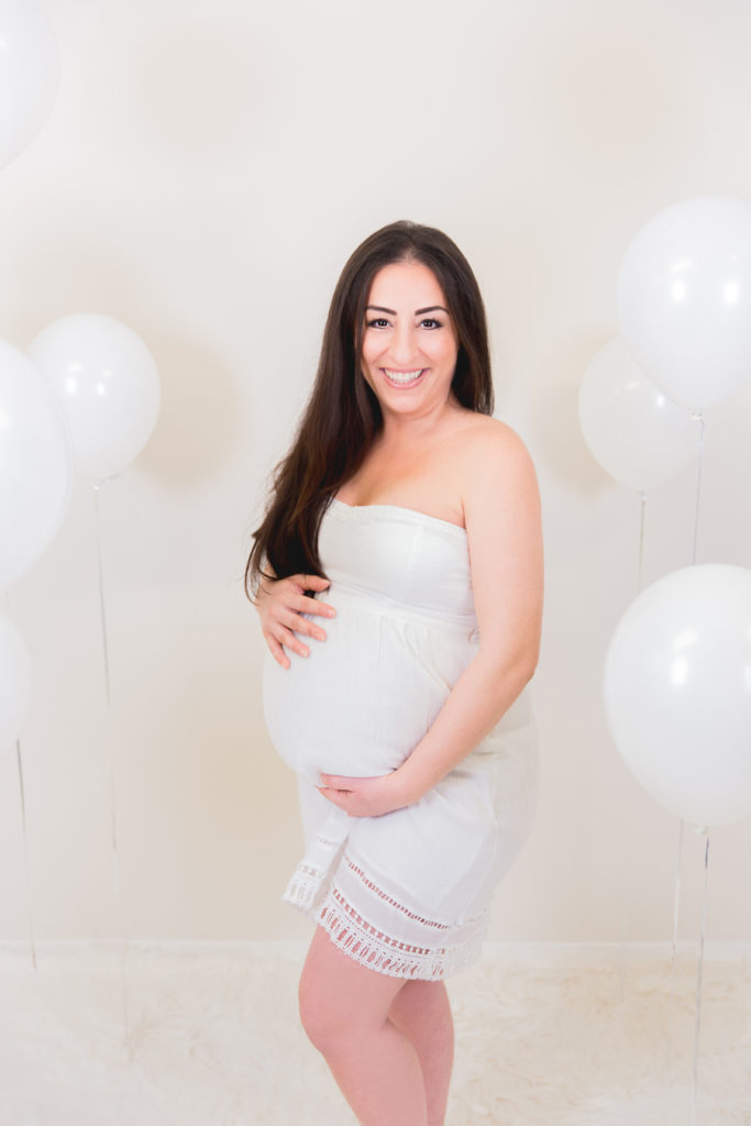 Strahlende werdende Mutter mit Luftballons