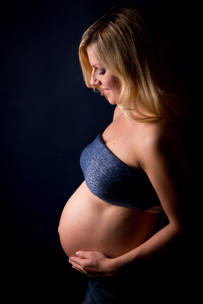 Babybauch im Fokus mit schwarzem Hintergrund