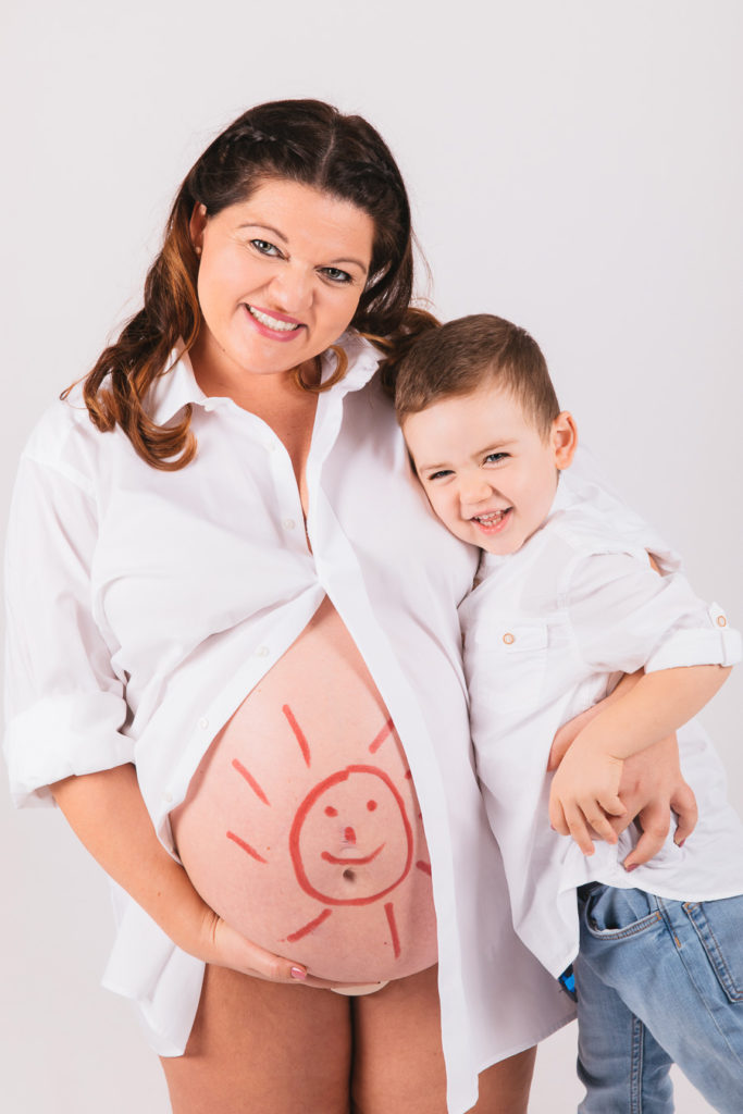 Mutter mit Kind und Babybauch mit Sonne darauf